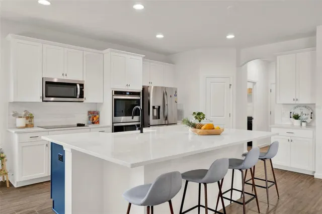 a kitchen with stainless steel appliances a white table chairs and a refrigerator