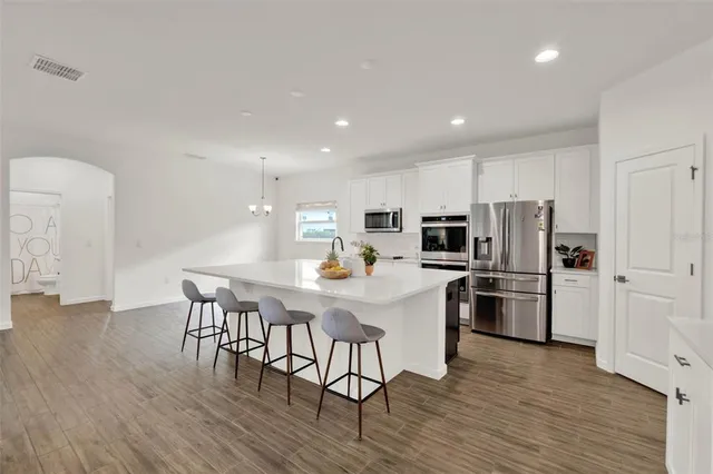 a kitchen with stainless steel appliances a refrigerator a stove a microwave oven a sink with island and chairs with wooden floor