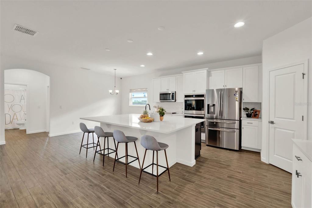 533 Avila Place Howey-in-the-Hills, FL 34737 - Photo 14 of 42 a kitchen with stainless steel appliances a refrigerator a stove a microwave oven a sink with island and chairs with wooden floor