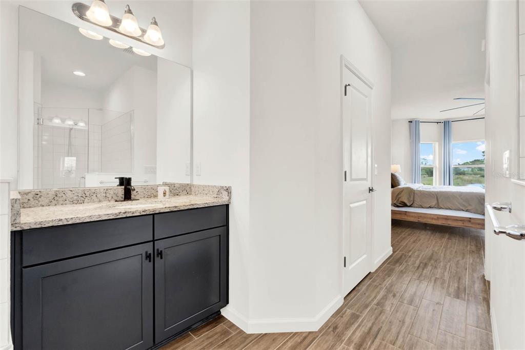 533 Avila Place Howey-in-the-Hills, FL 34737 - Photo 24 of 42 a en suite bathroom with a double vanity sink a mirror and a shower