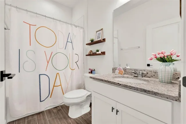 a bathroom with a granite countertop sink a toilet and a shower