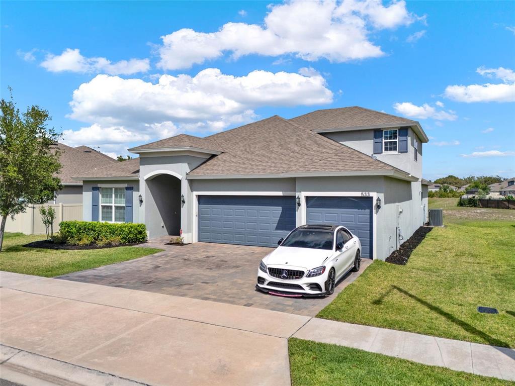 533 Avila Place Howey-in-the-Hills, FL 34737 - Photo 3 of 42 a view of a white house with a big yard and large trees