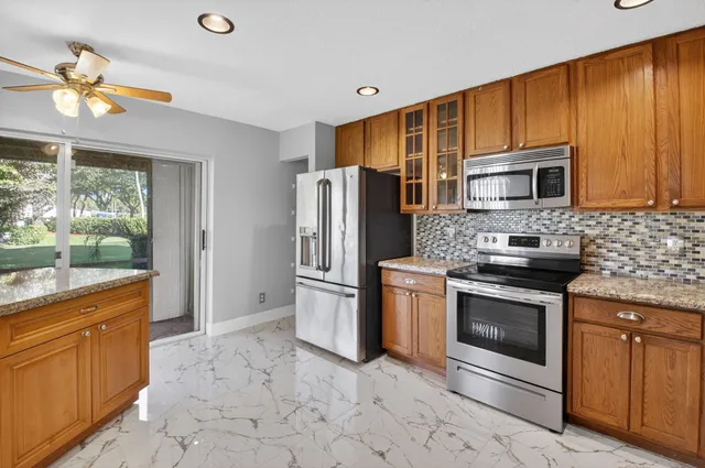 a kitchen with stainless steel appliances granite countertop a refrigerator and a stove top oven