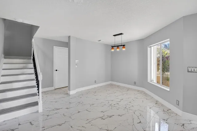 a view of an empty room with stairs and a window