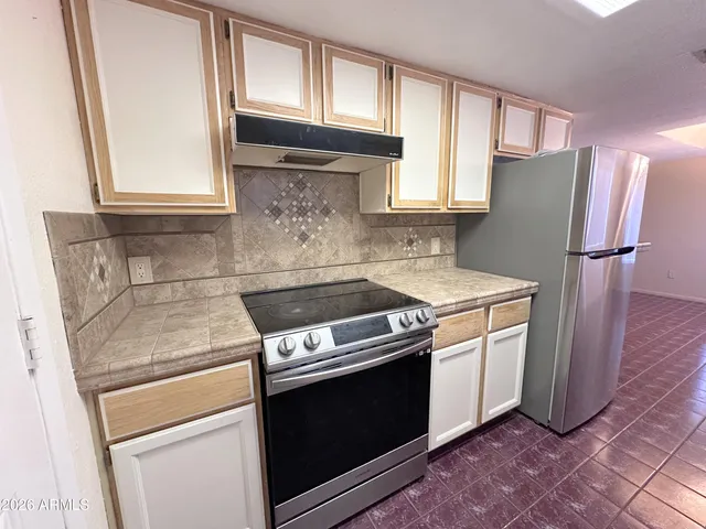 a kitchen with granite countertop a stove a sink dishwasher and a refrigerator with wooden floor