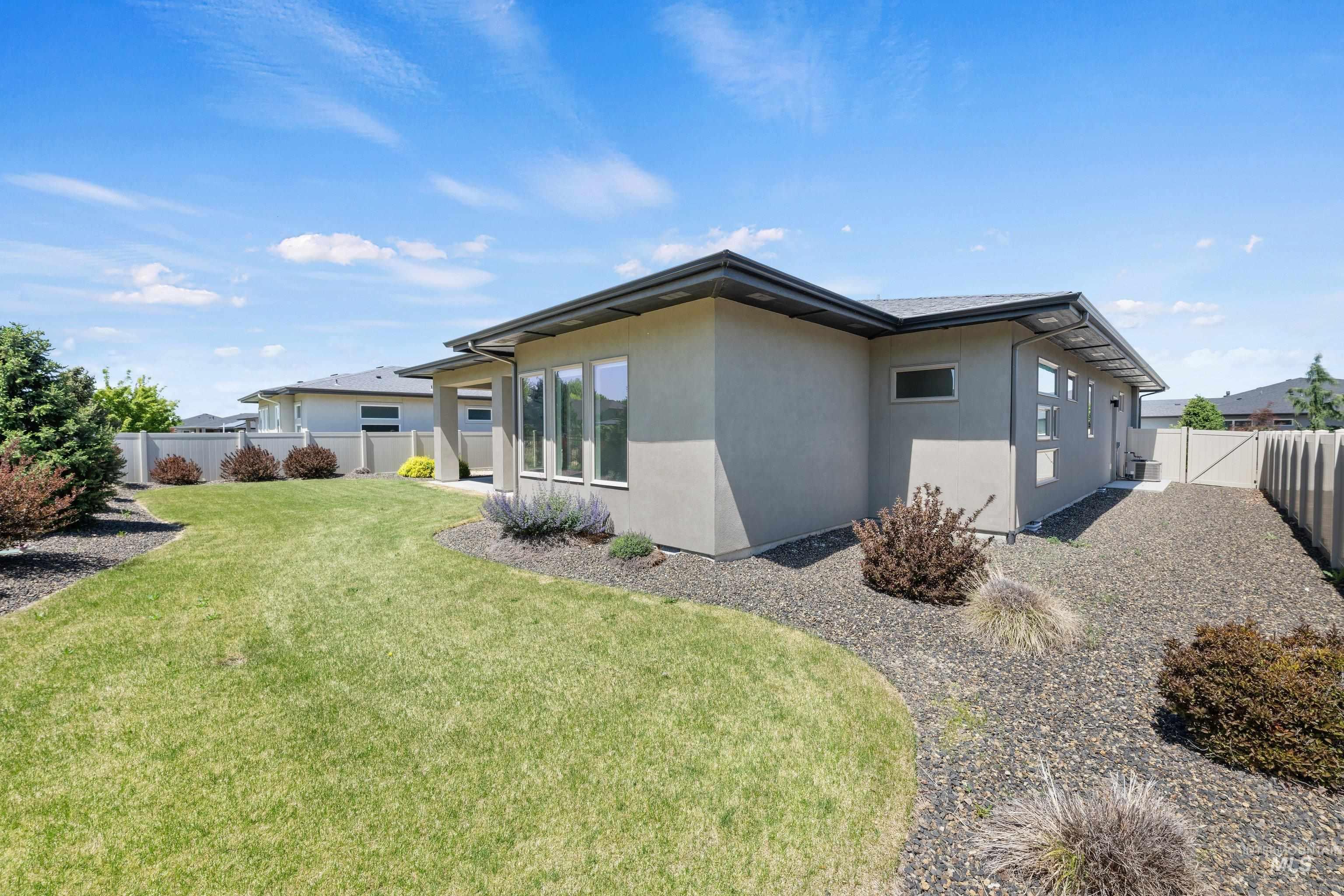 4447 East Copper Point Drive Meridian, ID 83642 - Photo 35 of 41 Rear exterior featuring a stucco facade, multiple windows, dark roofline, and a gravel perimeter