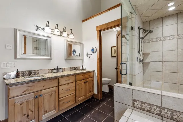 a bathroom with a double vanity sink mirror and shower