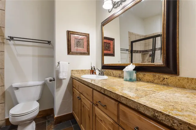 a bathroom with a granite countertop sink mirror vanity and toilet