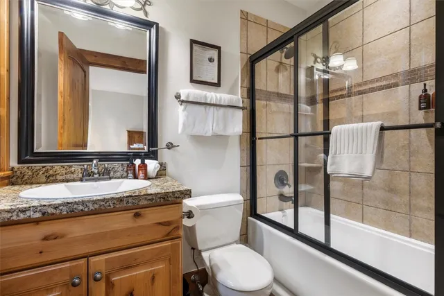 a bathroom with a granite countertop sink mirror vanity and toilet