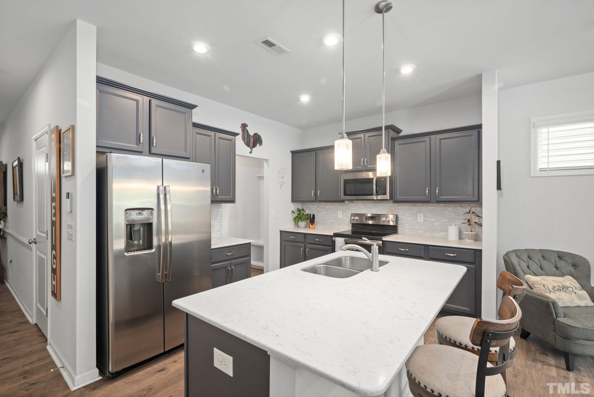 3614 Water Mist Lane Raleigh, NC 27604 - Photo 10 of 50 a kitchen with stainless steel appliances a refrigerator a sink a stove a dining table and chairs