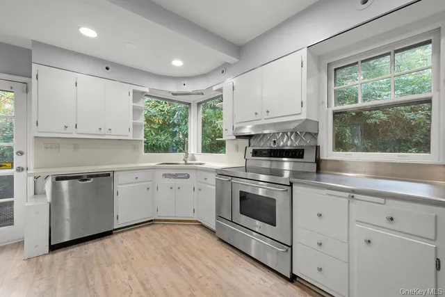 a kitchen with white cabinets stainless steel appliances and a window