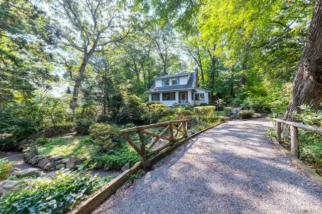 a view of a house with large trees and a yard