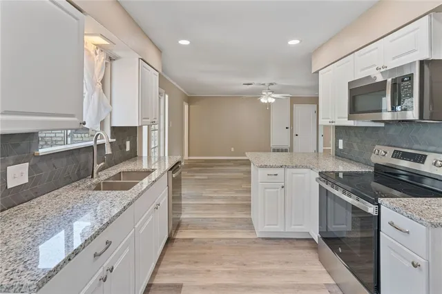 a large kitchen with stainless steel appliances granite countertop a sink and dishwasher stove a oven with wooden cabinets