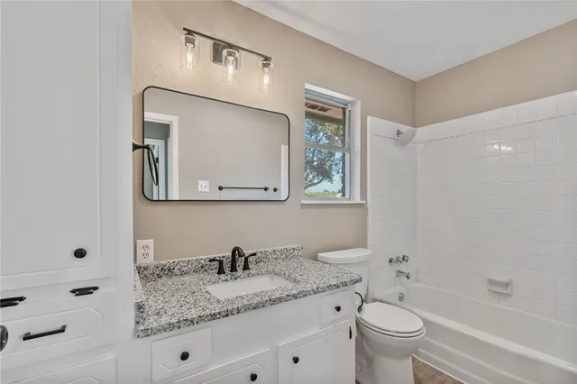 a bathroom with a granite countertop sink mirror vanity bathtub and a toilet