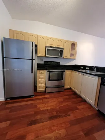 a kitchen with granite countertop a refrigerator and a stove top oven