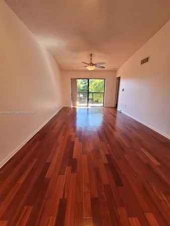a view of empty room with wooden floor and fan