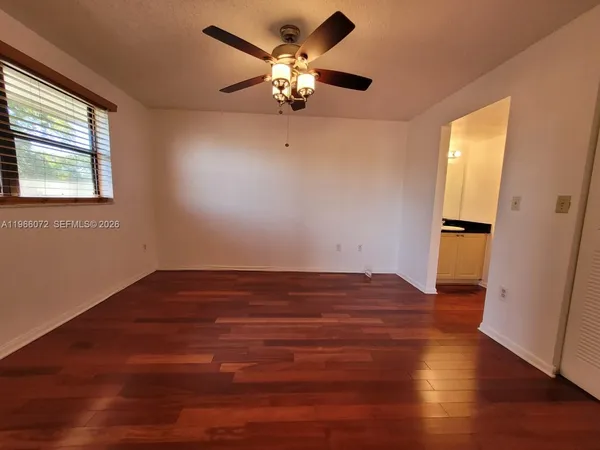 a view of an empty room with wooden floor and a window