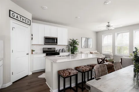 a kitchen with stainless steel appliances granite countertop a stove top oven a sink a dining table and chairs
