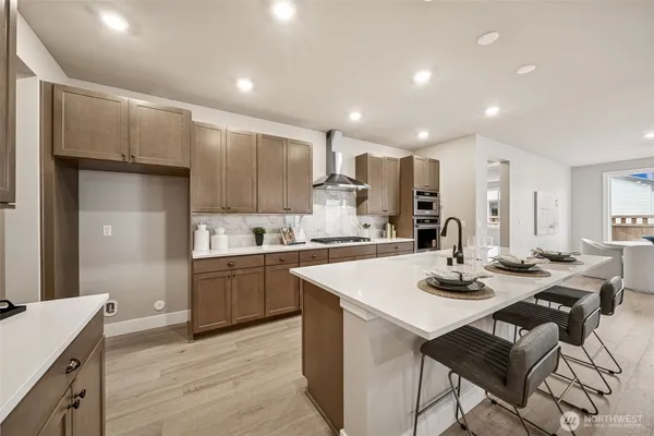 a kitchen with a sink a stove a refrigerator and white cabinets with wooden floor