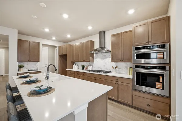 a kitchen with stainless steel appliances kitchen island granite countertop a sink a stove a microwave and island