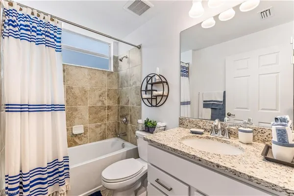 a bathroom with a granite countertop sink mirror vanity and toilet
