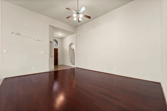 an empty room with wooden floor and ceiling fan