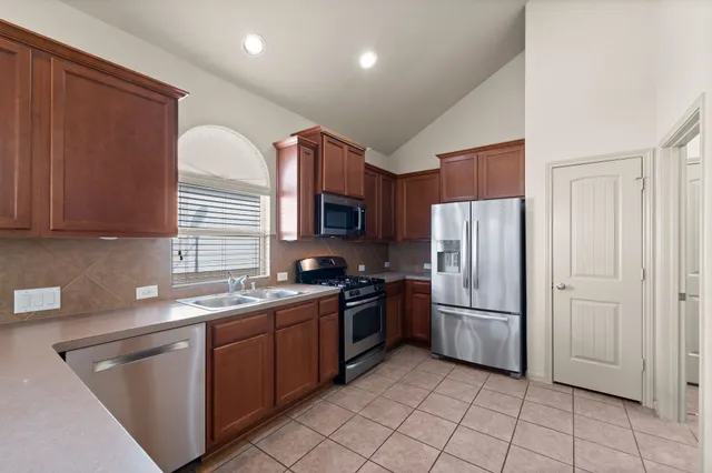 a kitchen with stainless steel appliances granite countertop a refrigerator sink and stove