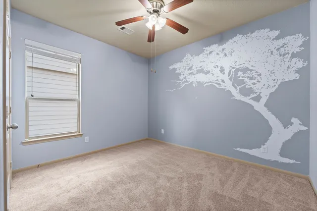 an empty room with a chandelier fan and windows