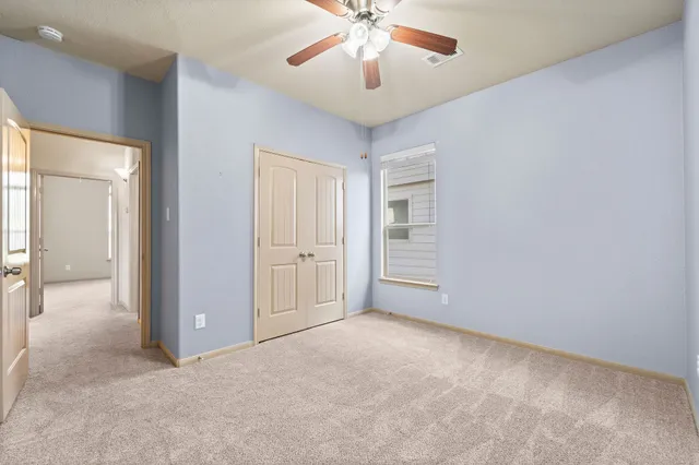 an empty room with chandelier fan and windows