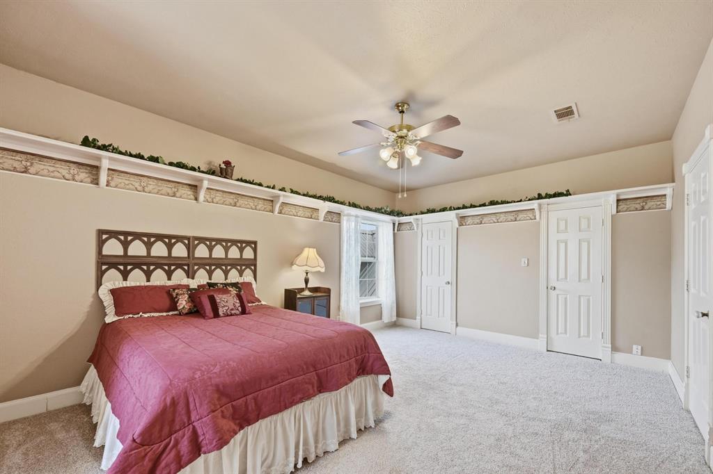707 Cullins Road Rockwall, TX 75032 - Photo 26 of 40 a bedroom with a large bed and a chandelier
