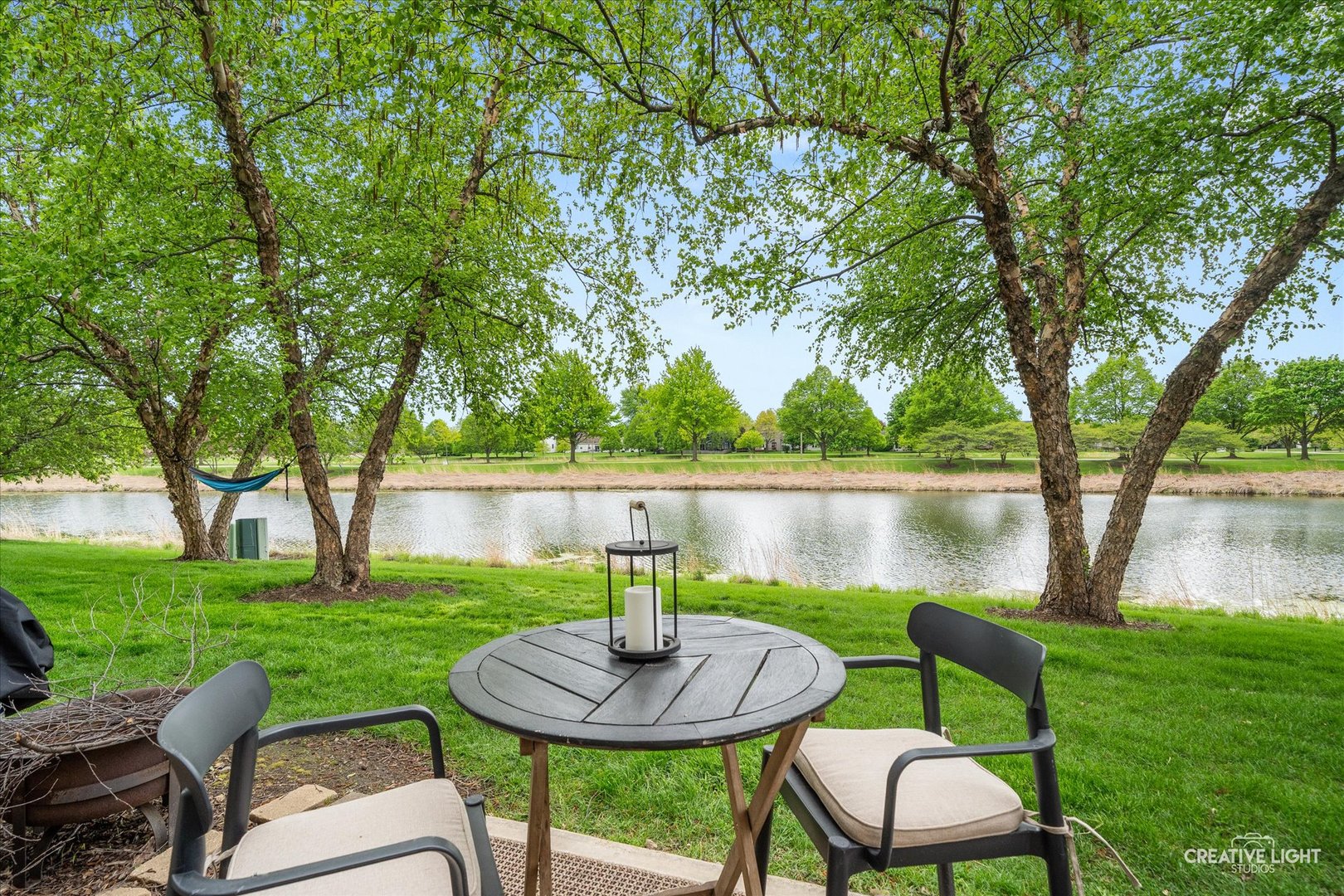 24019 Pear Tree Circle Plainfield, IL 60585 - Photo 18 of 20 a view of a lake with table and chairs potted plants and a large tree