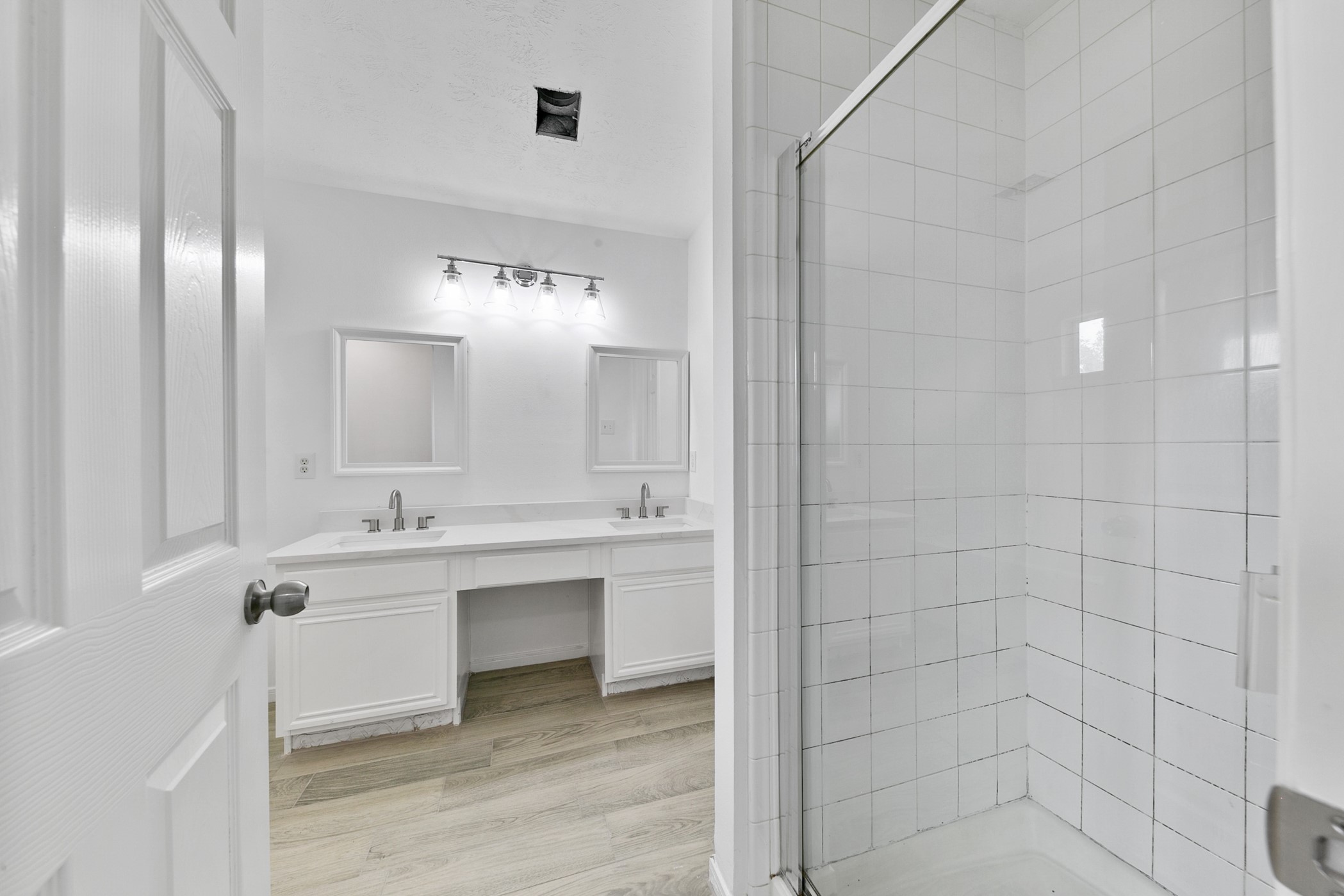 12014 Raven View Drive Houston, TX 77067 - Photo 25 of 29 This bathroom features a modern, clean design with a double vanity, large mirrors, stylish lighting, and a spacious glass-enclosed shower. Bright and inviting, it offers ample space and contemporary fixtures.