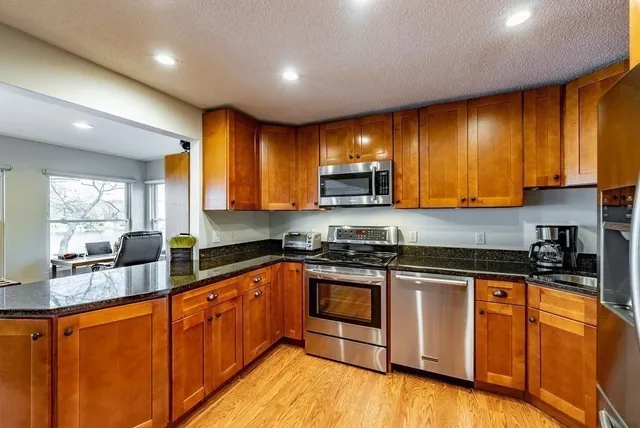 a kitchen with stainless steel appliances granite countertop wooden cabinets a stove top oven a sink and dishwasher