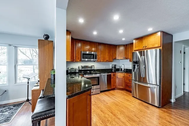 a kitchen with stainless steel appliances granite countertop a refrigerator a stove top oven a sink cabinets and wooden floor