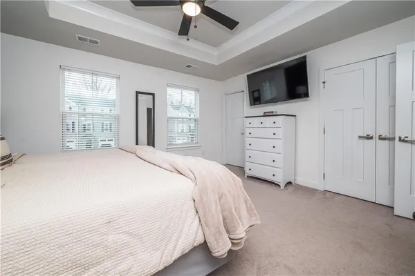 a bedroom with a bed a flat tv and a dresser