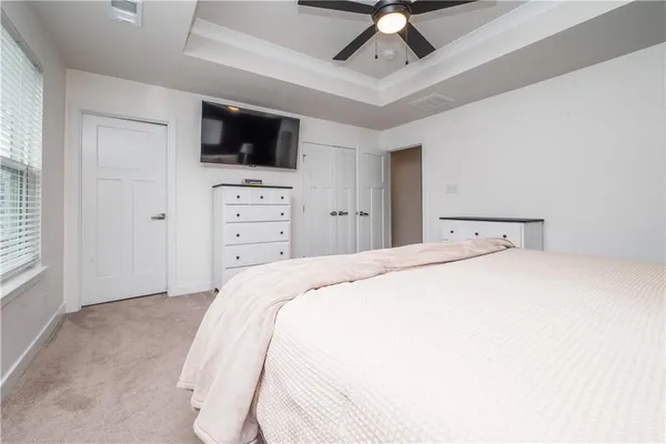 a bedroom with a bed and a flat tv screen on dresser