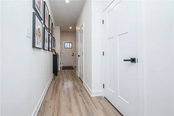 a view of a hallway with wooden floor and a bathroom