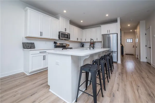 a kitchen with stainless steel appliances a table chairs refrigerator and a stove top oven