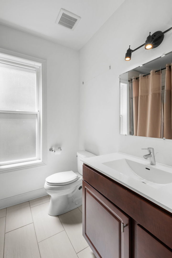 2649 West 21st Place Chicago, IL 60608 - Photo 7 of 26 a bathroom with a granite countertop sink a toilet a mirror and a bathtub