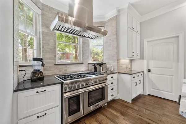 a kitchen with stainless steel appliances white cabinets and a wooden floors