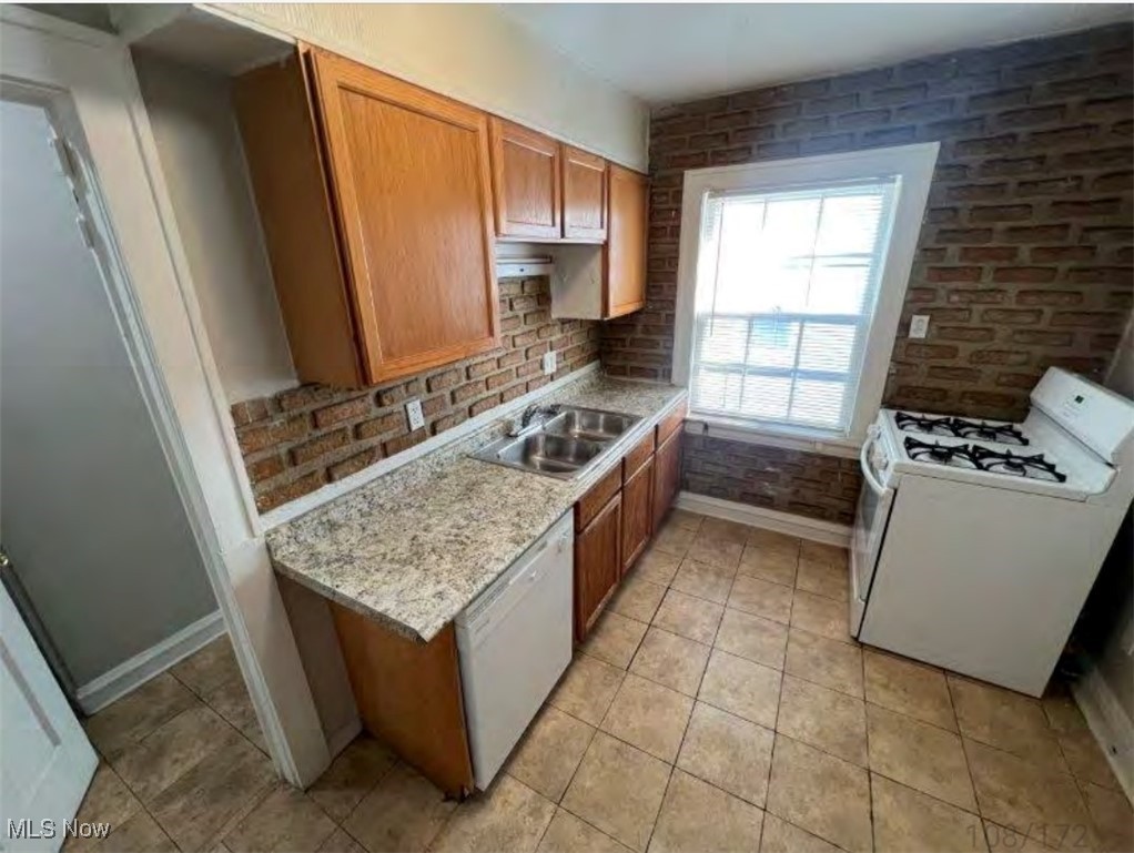 3579 Riedham Road Cleveland, OH 44120 - Photo 4 of 13 Kitchen featuring white appliances, light tile patterned floors, light stone counters, sink, and brick wall