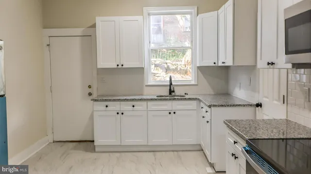 a kitchen with granite countertop white cabinets and a sink