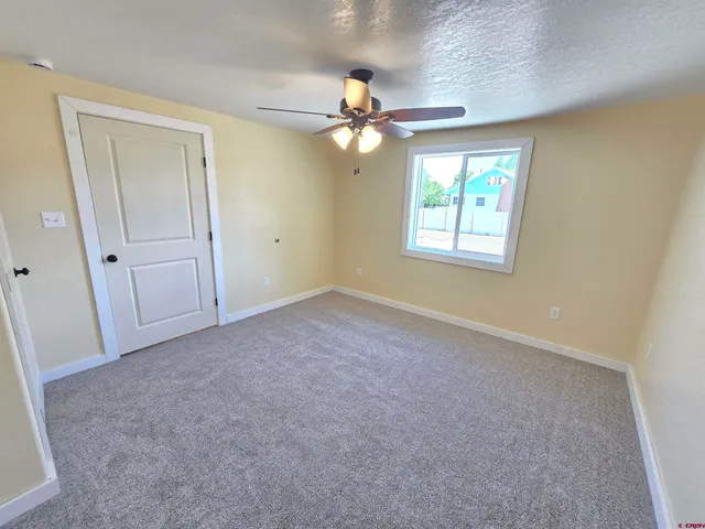 an empty room with windows and fan
