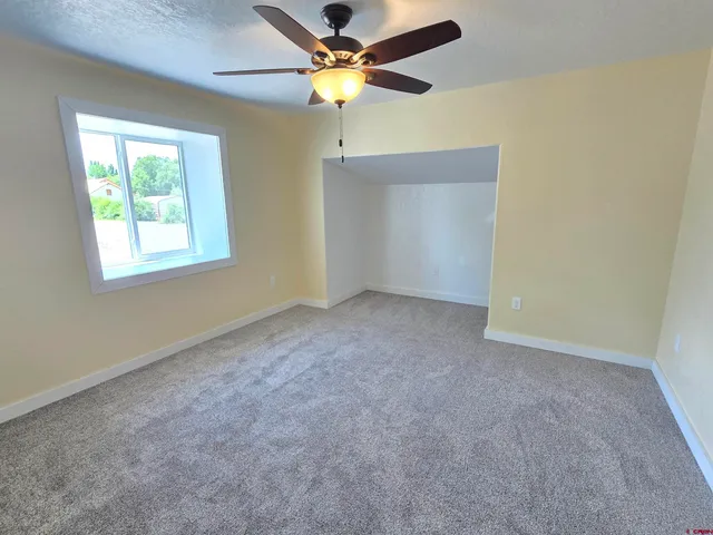 an empty room with a window and a fan
