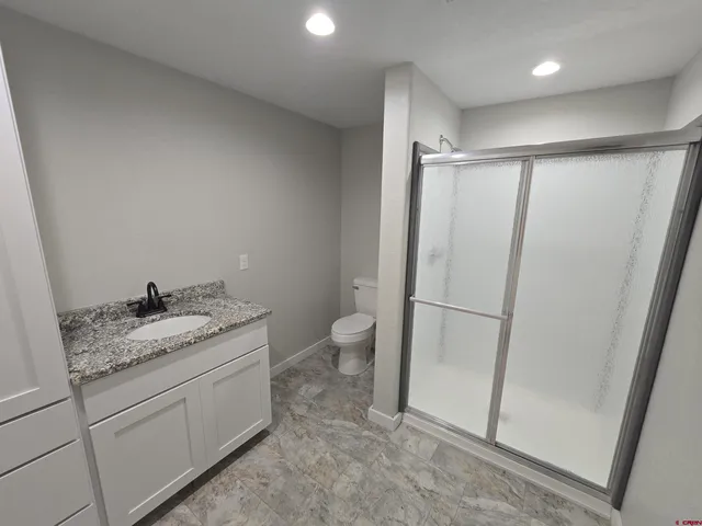 a bathroom with a granite countertop sink toilet and shower