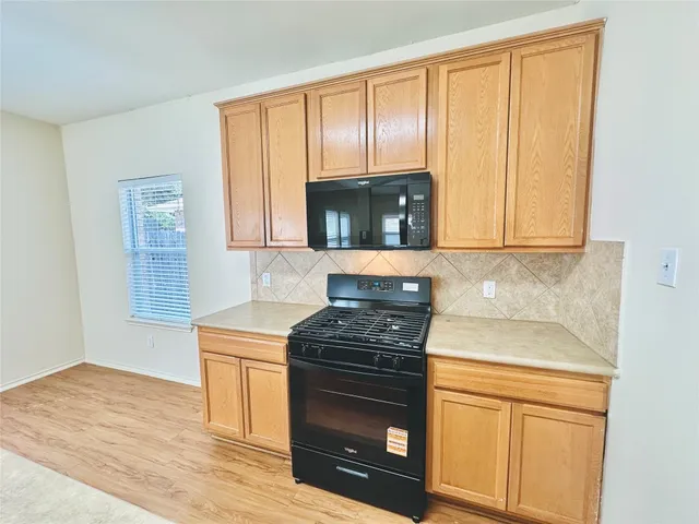 a kitchen with granite countertop wooden cabinets and a stove top oven