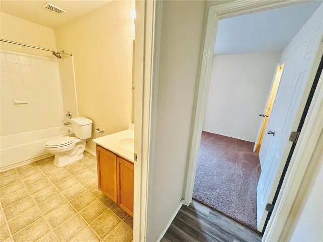 a view of an empty room with wooden floor and closet