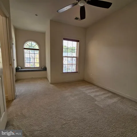 an empty room with chandelier fan and windows