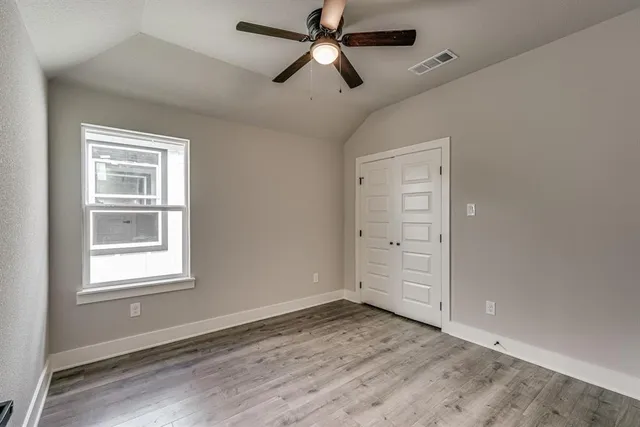 a view of empty room with wooden floor and fan