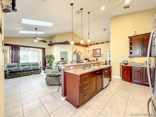 a living room with couches a flat screen tv and kitchen view